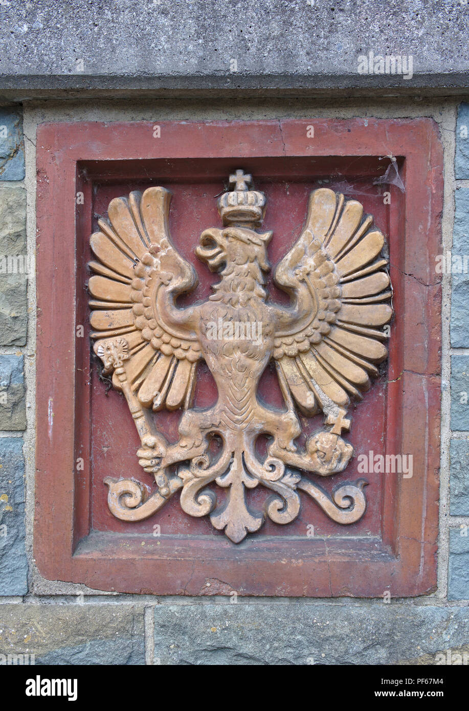 Deisfeld, Germania - agosto 2nd, 2018 - rilievo araldico in beige su sfondo di colore rosso che raffigura un aquila imperiale che indossa una corona e tenendo un scettro un Foto Stock