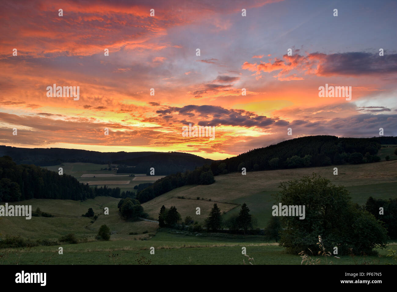 Sauerland, Germania - Drammatico rosa e arancione tramonto su una verde vallata con colline boscose della distanza Foto Stock