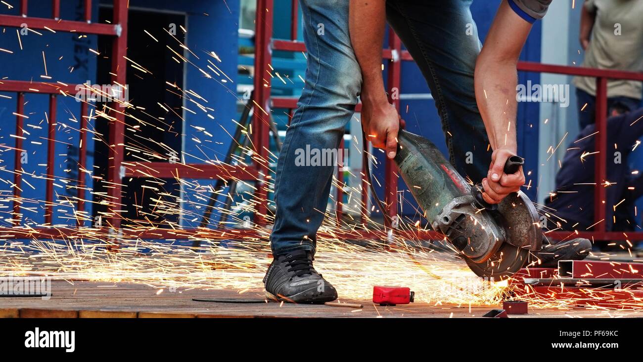 Lavoratore di metallo taglio acciaio sul sito in costruzione, scintille volanti Foto Stock
