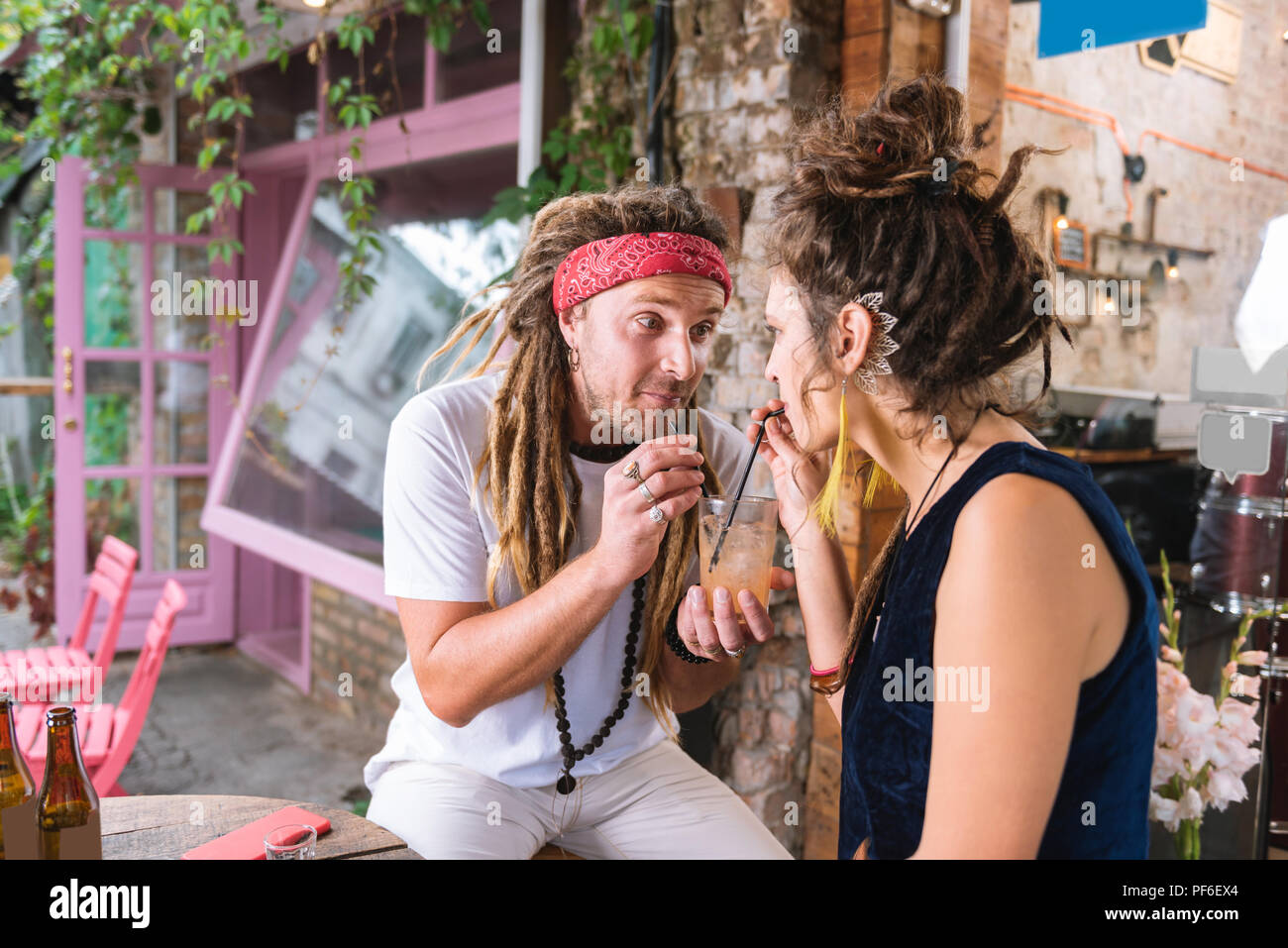 Hippie uomo unisce la sua ragazza bere cocktail Foto Stock