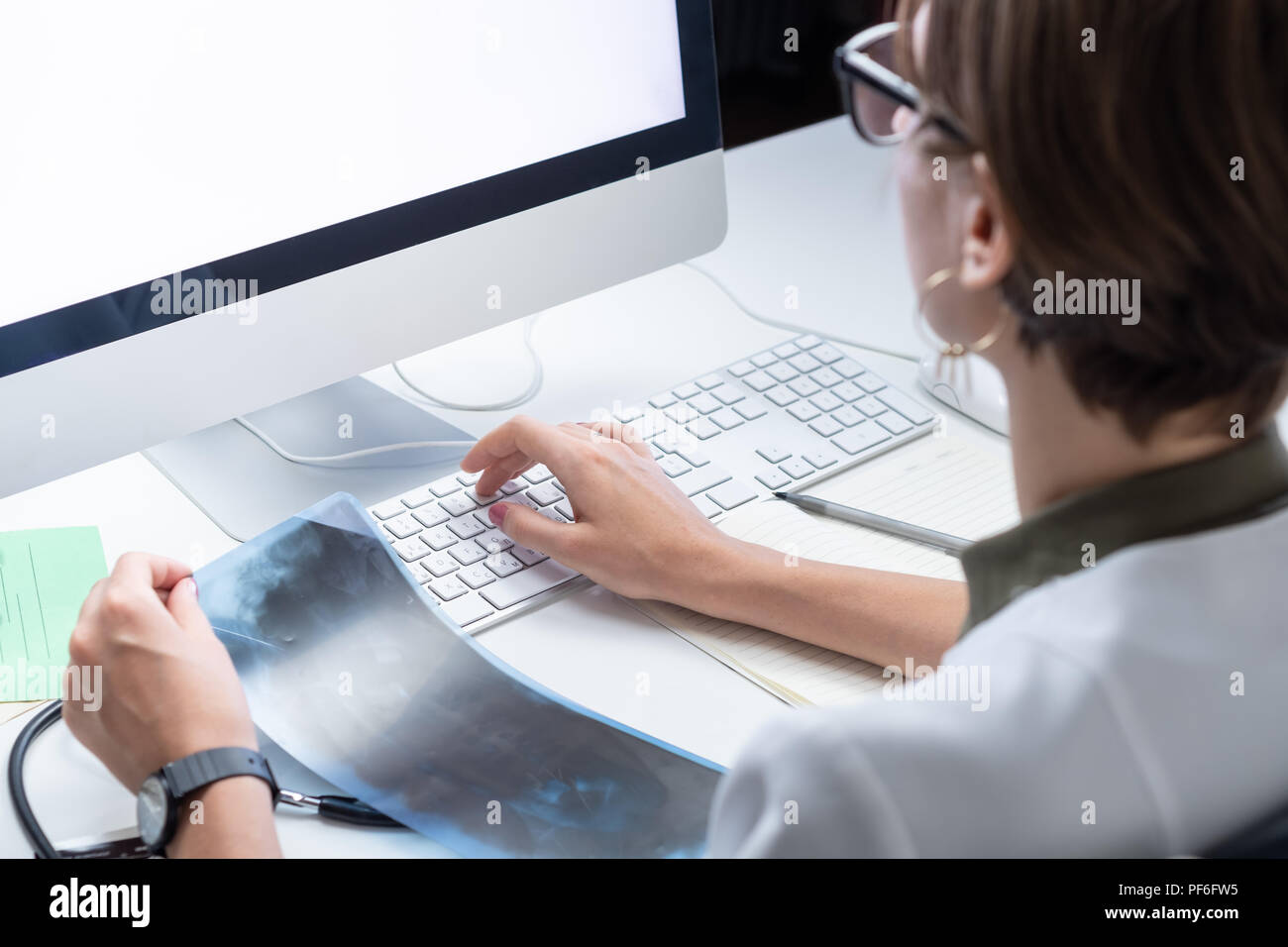 Sanità digitale concetto: giovane medico lavorando a un computer desktop. Femmina al professionista medico moderno ufficio medico esame x-ray e ta Foto Stock