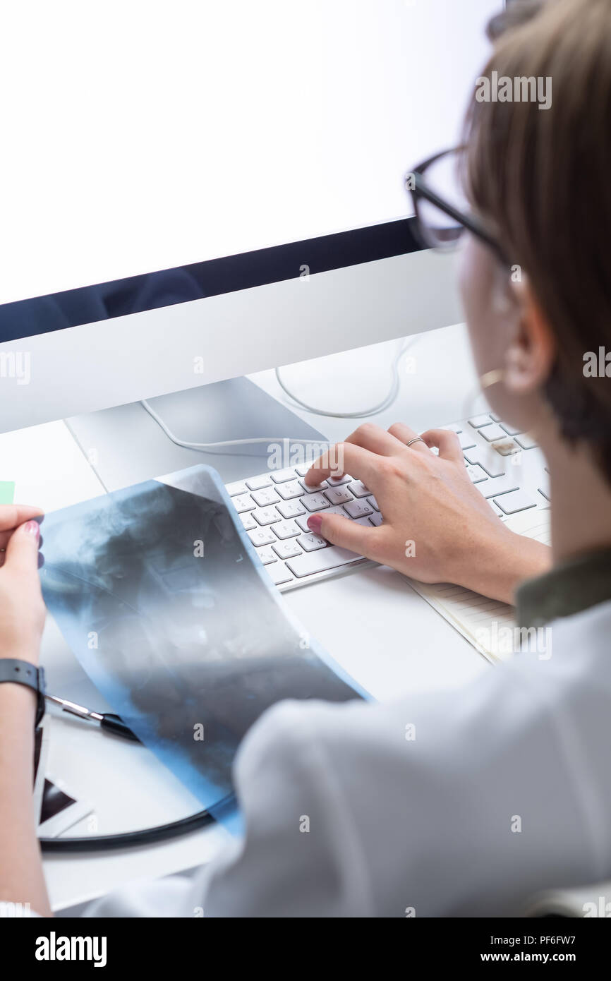 Sanità digitale concetto: giovane medico lavorando a un computer desktop. Femmina al professionista medico moderno ufficio medico esame x-ray e ta Foto Stock
