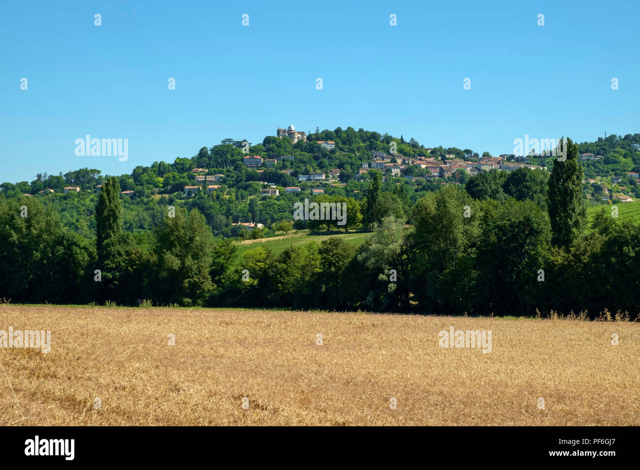 Guardando attraverso i campi estivi verso Colle penne d'Agenais e la sua Cattedrale di Notre Dame de Peyragude basilica con la sua cupola di argento nelle zone rurali a Lot et Garonne, Francia. Foto Stock
