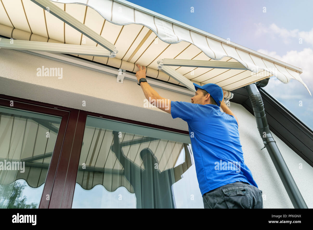 Lavoratore installare una tenda sul muro di casa sopra la finestra terrazza Foto Stock