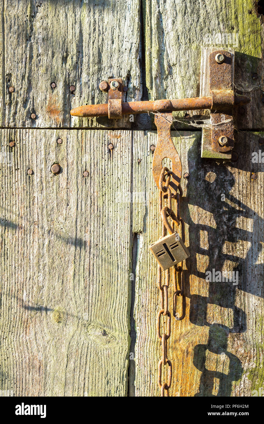 Vecchia serratura e la catena sul weathered fienile porta - Francia. Foto Stock