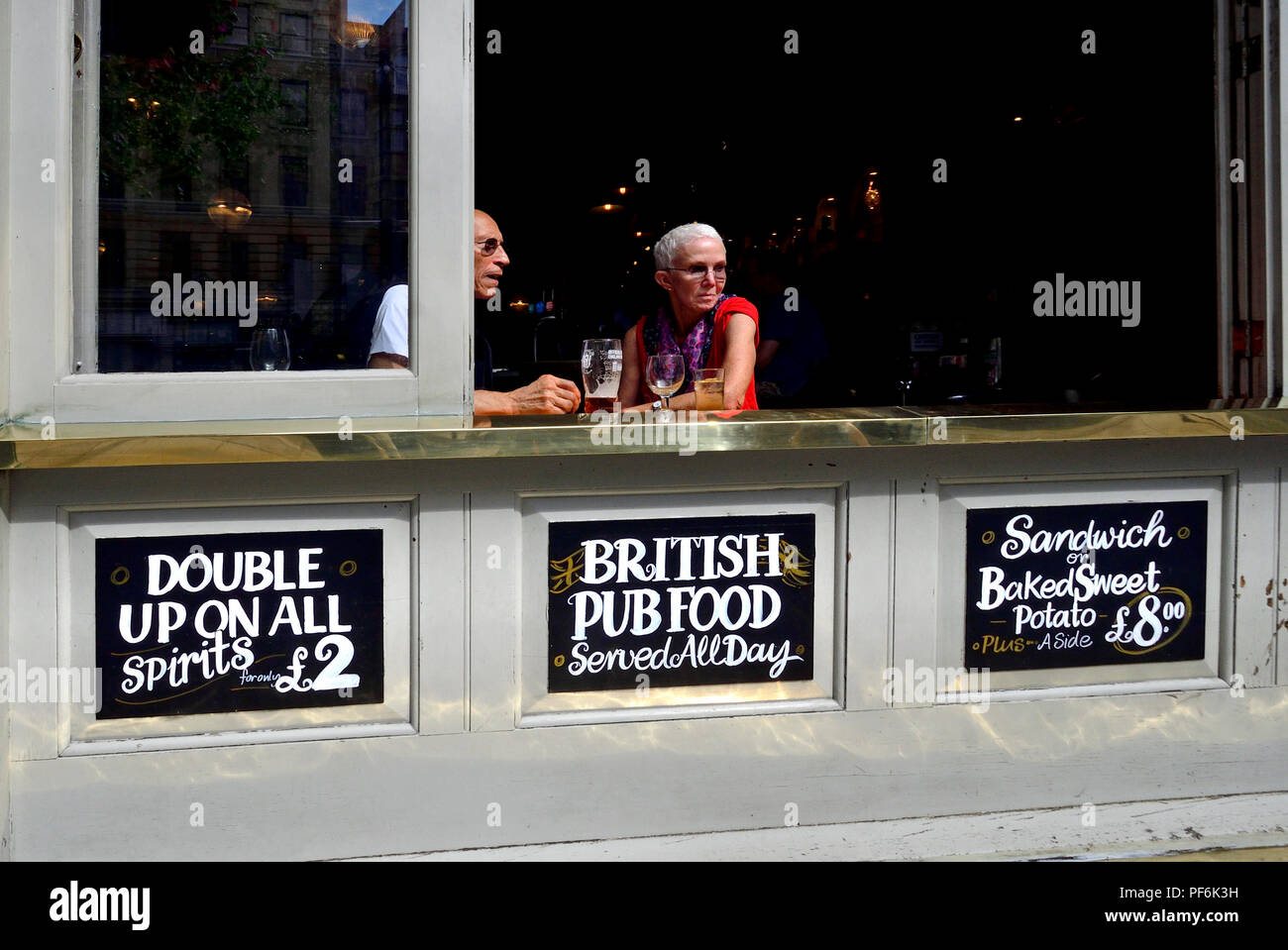 La gente alla finestra aperta del Garrick Arms pub in Charing Cross Road, Londra, Inghilterra, Regno Unito. Foto Stock
