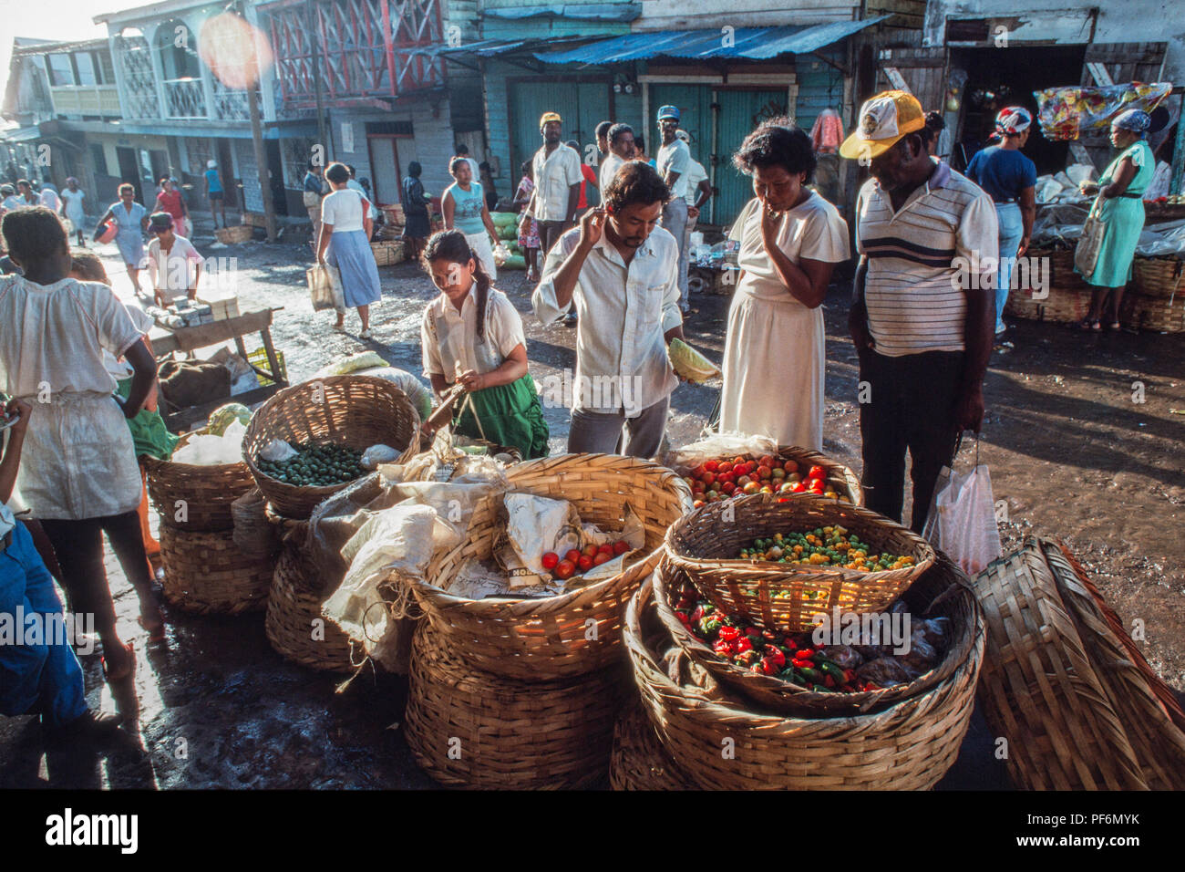 Persone che comprano e vendono prodotti in un mercato all'aperto in una posizione tropicale con cesti di verdure colorate. Foto Stock