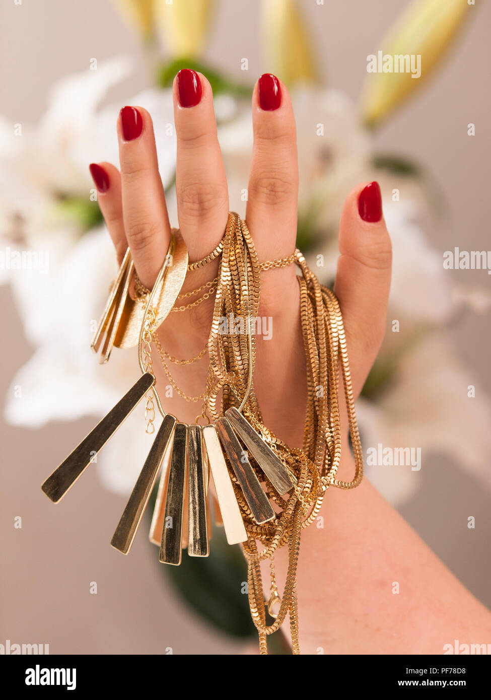 Mano con belle piste per chiodi holding gioielli in oro Foto Stock