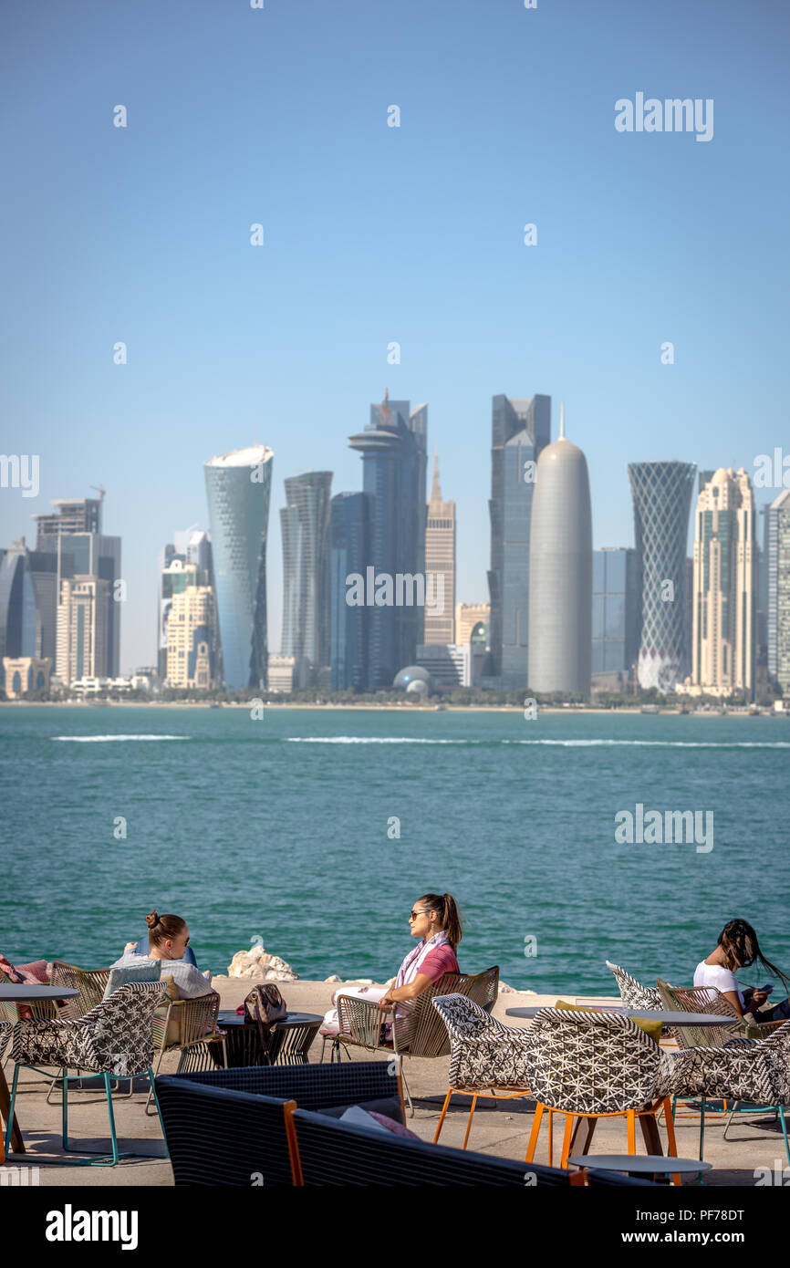 Doha, Qatar - Jan 8 2018 - La gente del posto e turisti che si godono un cafe bar con Doha skyline in background in un cielo blu giorno, Doha in Qatar Foto Stock