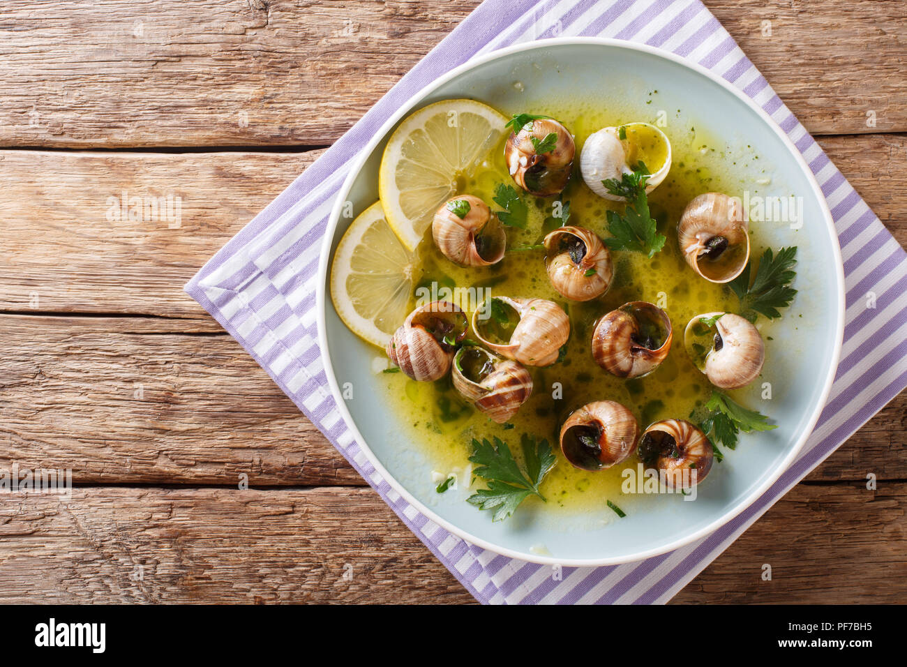 Cucina francese: Escargot con burro, erbe e aglio close-up su una piastra su un tavolo. parte superiore orizzontale vista da sopra Foto Stock