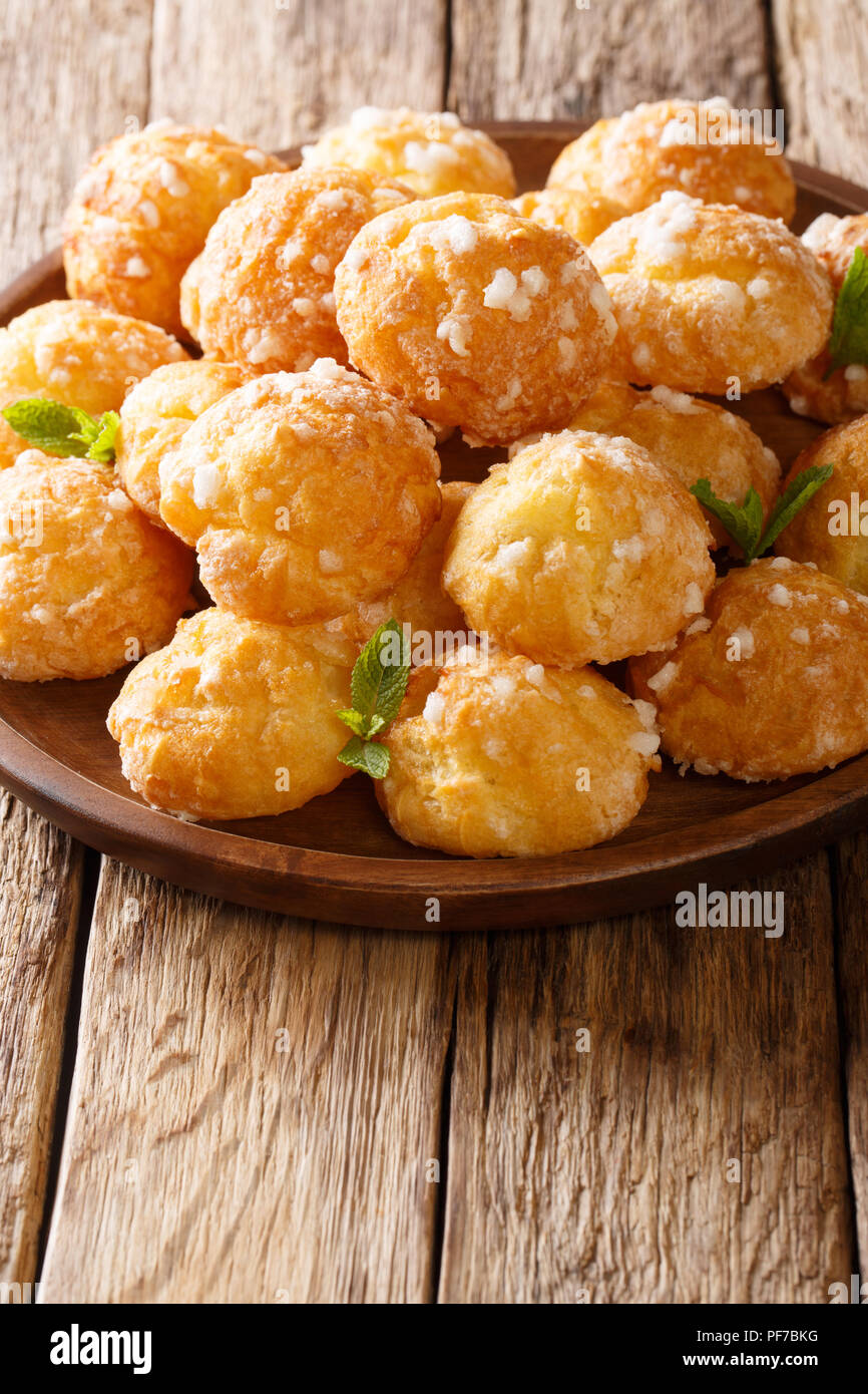 Chouquette Delicato dessert è decorata con zucchero di perla e menta closeup su una tavola verticale. Foto Stock