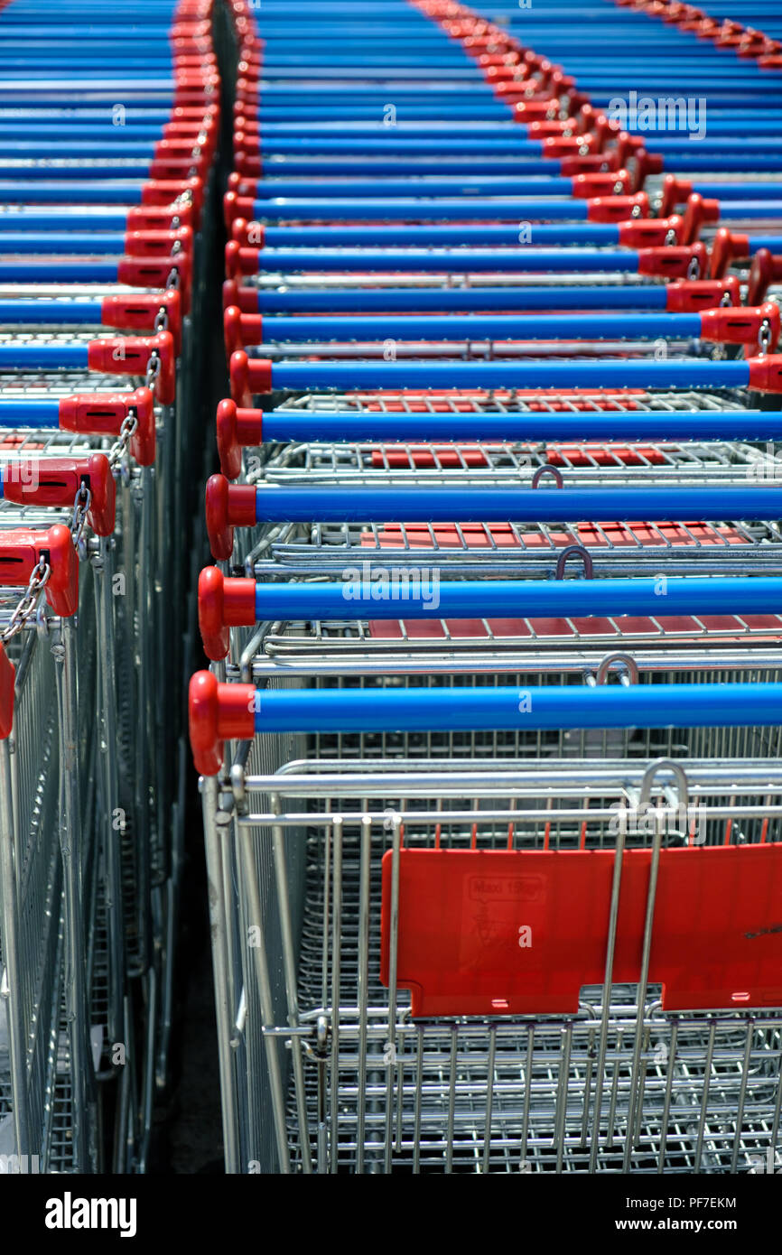 Il rosso e il blu supermercato shopping carts trollie parcheggiato insieme al di fuori del negozio. Piacenza, Italia, Europa. Foto Stock