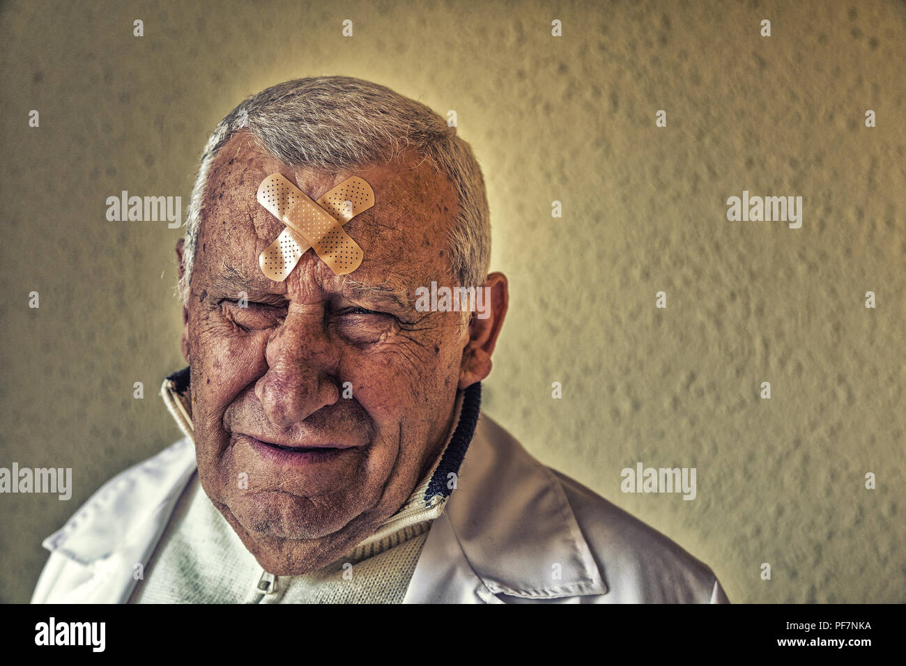 Triste vecchio medico con patch sulla fronte Foto Stock