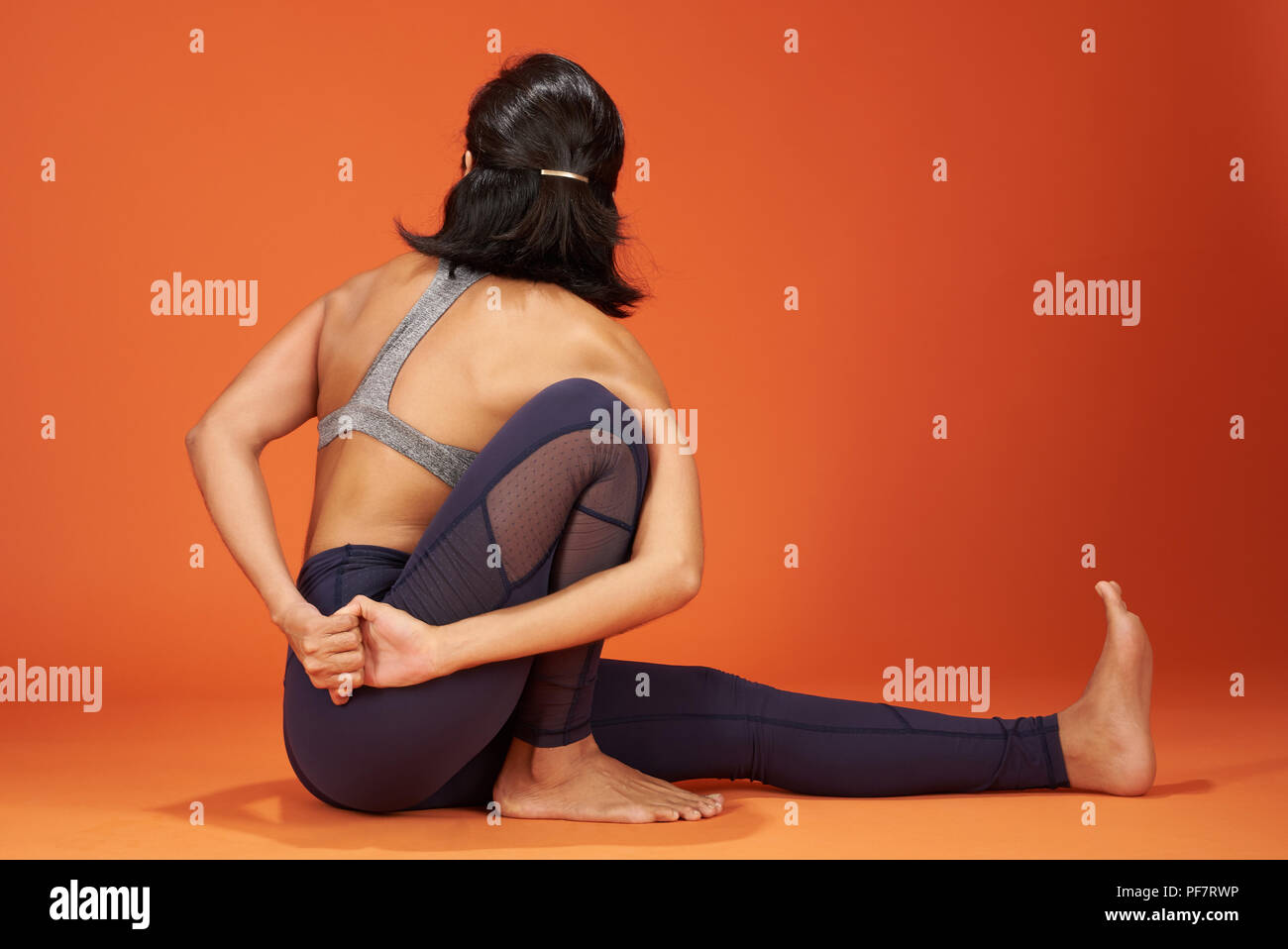 Marichi's Yoga asana pongono donna mostra su orange Colore di sfondo Foto Stock