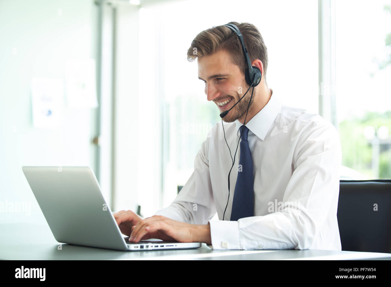 Felice giovane maschio supporto clienti dirigenti che lavorano in ufficio. Foto Stock