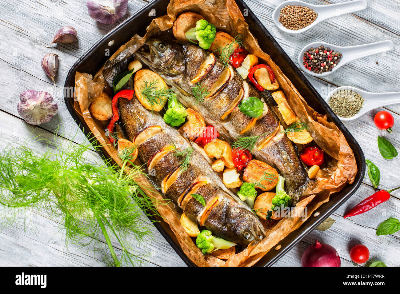 Pesci trote al forno con patate, broccoli, limone, pomodori Foto Stock