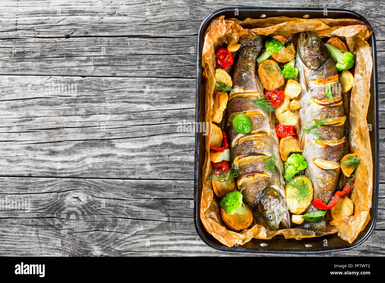 Trote intere pesci alla griglia con patate, broccoli, limone, pomodori, vista dall'alto Foto Stock