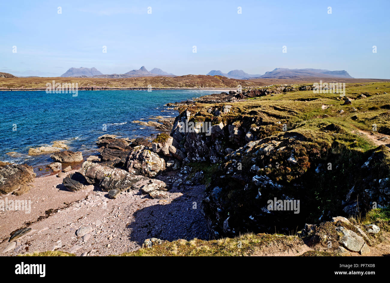 Vista attraverso la rocciosa di foreshore Achnahaird Bay, Coigach, Highlands scozzesi, Inverpolly monti all'orizzonte. Foto Stock