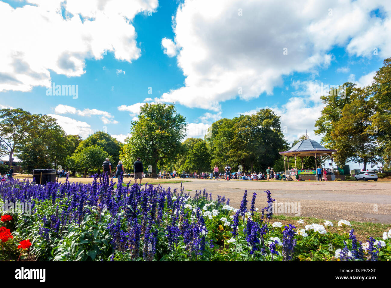 Una band suona un concerto gratuito nella band stand in giardini Alexandra in Windsor, Regno Unito. Persone sedersi su sedie pieghevoli, benchses e il pavimento a guardare. Foto Stock