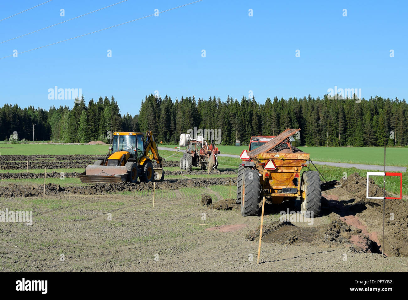 Trattori ed escavatori sul campo facendo un drenaggio. Foto Stock