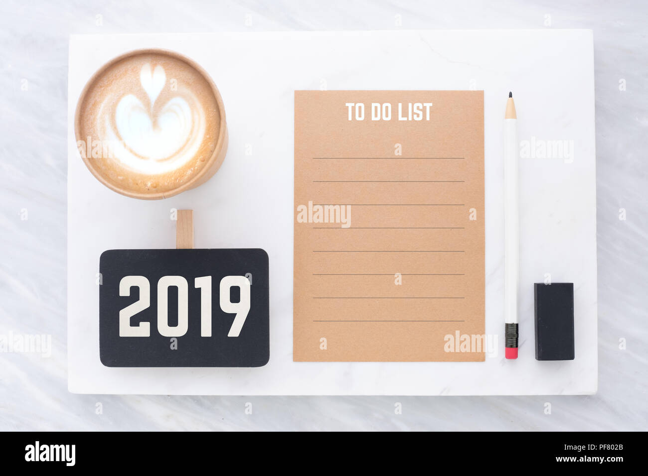2019 Lista da fare su marrone riciclare carta con matita,clip,lavagna matita,eraser e tazza di caffè in marmi bianchi e grigi table.mock up per aggiunta di testo Foto Stock
