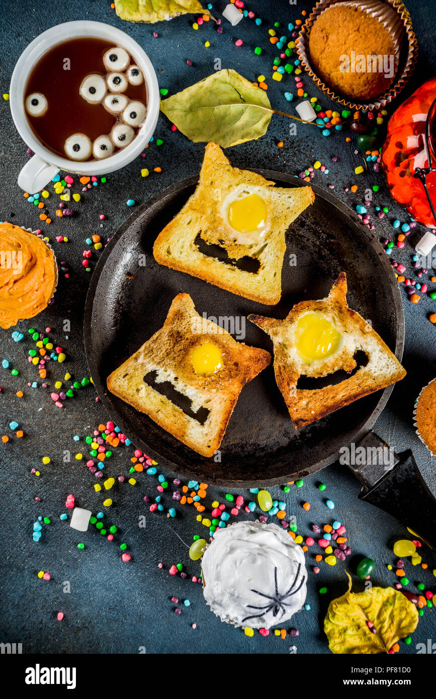 Divertente per bambini tratta per la festa di Halloween, un'idea per una festosa colazione. Panini toast con uova, guardando come creepy mostri, cioccolato caldo con m Foto Stock