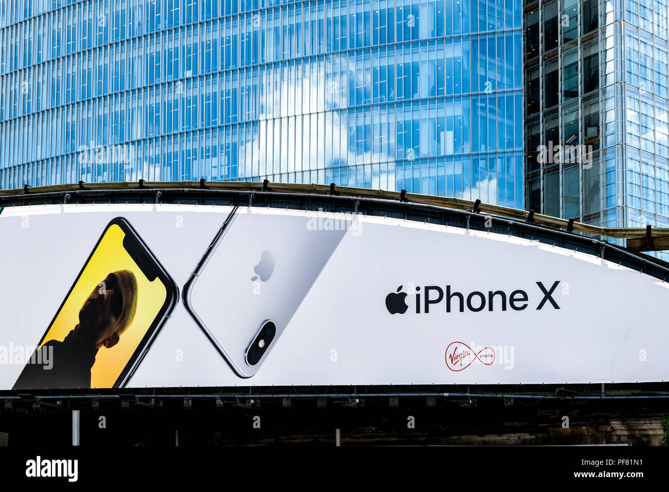 London, Regno Unito - 22 Giugno 2018: pubblicità Affissioni per iPhone X e Virgin Media su autostrada ponte stradale dietro il grattacielo moderno edificio Foto Stock