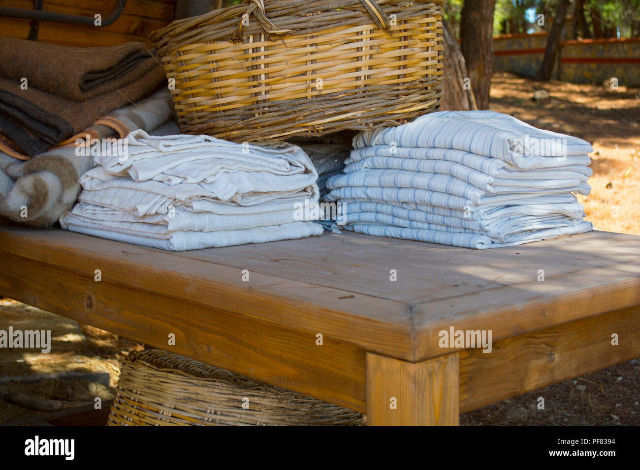 Asciugamani da bagno e coperta di colori diversi nel cesto di vimini sul tavolo di legno in giardino Foto Stock