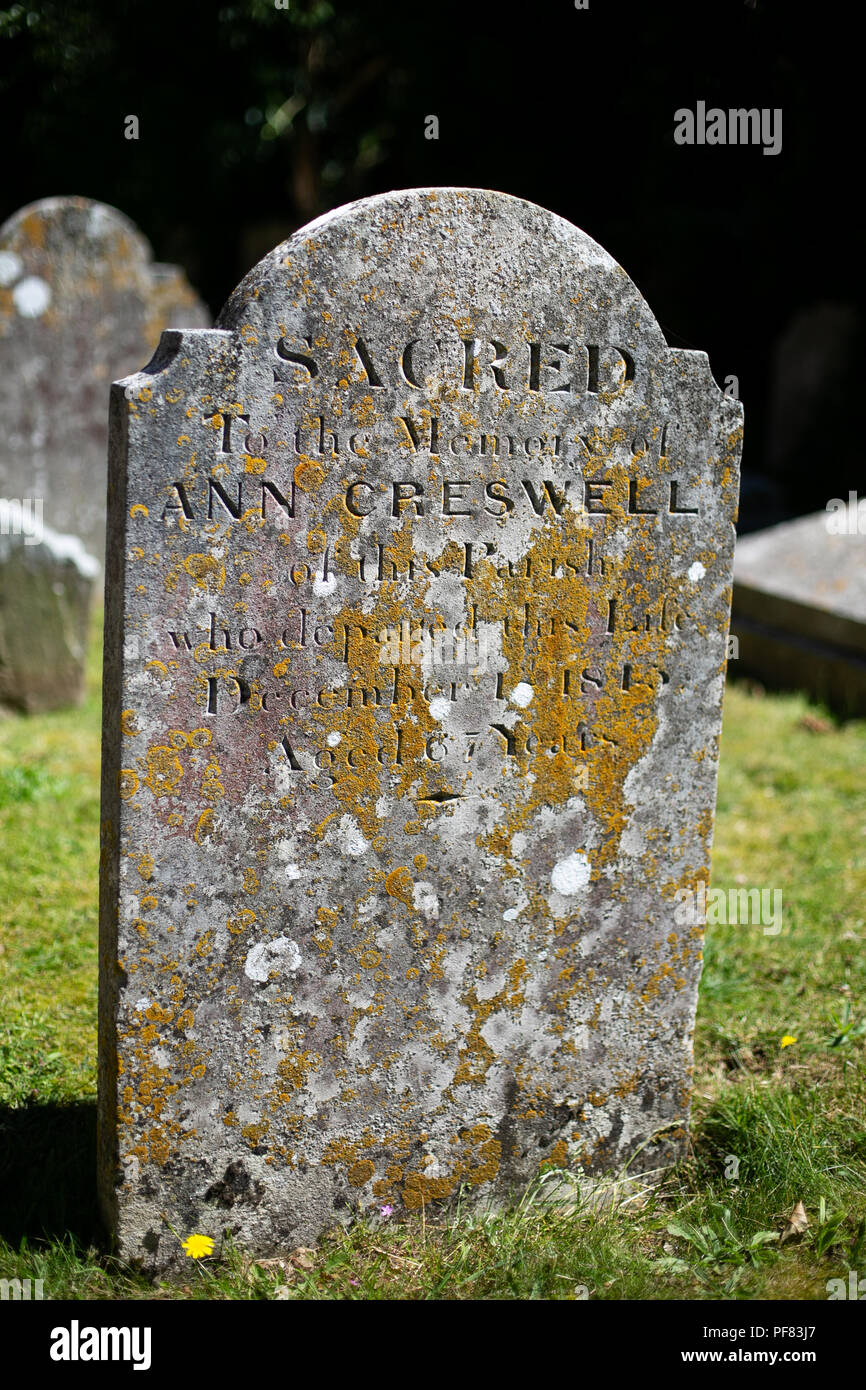 Ritratto di una lapide di età in un villaggio inglese sagrato coperto in MOSS Foto Stock