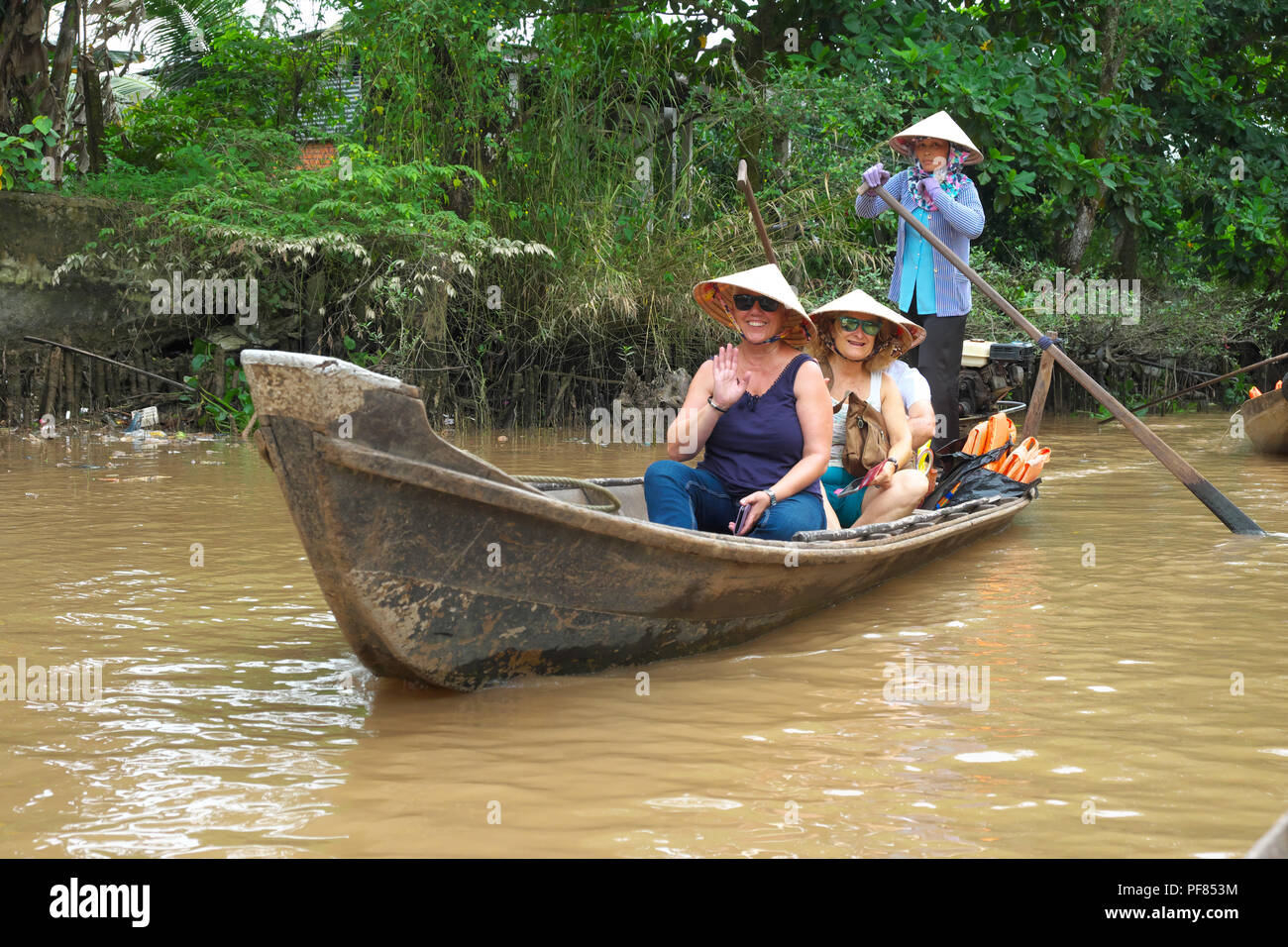 Il Vietnam turisti facendo una gita in barca vicino tCai essere nella regione del Delta del Mekong del Viet Nam con locale donna vecchia barca a remi Foto Stock