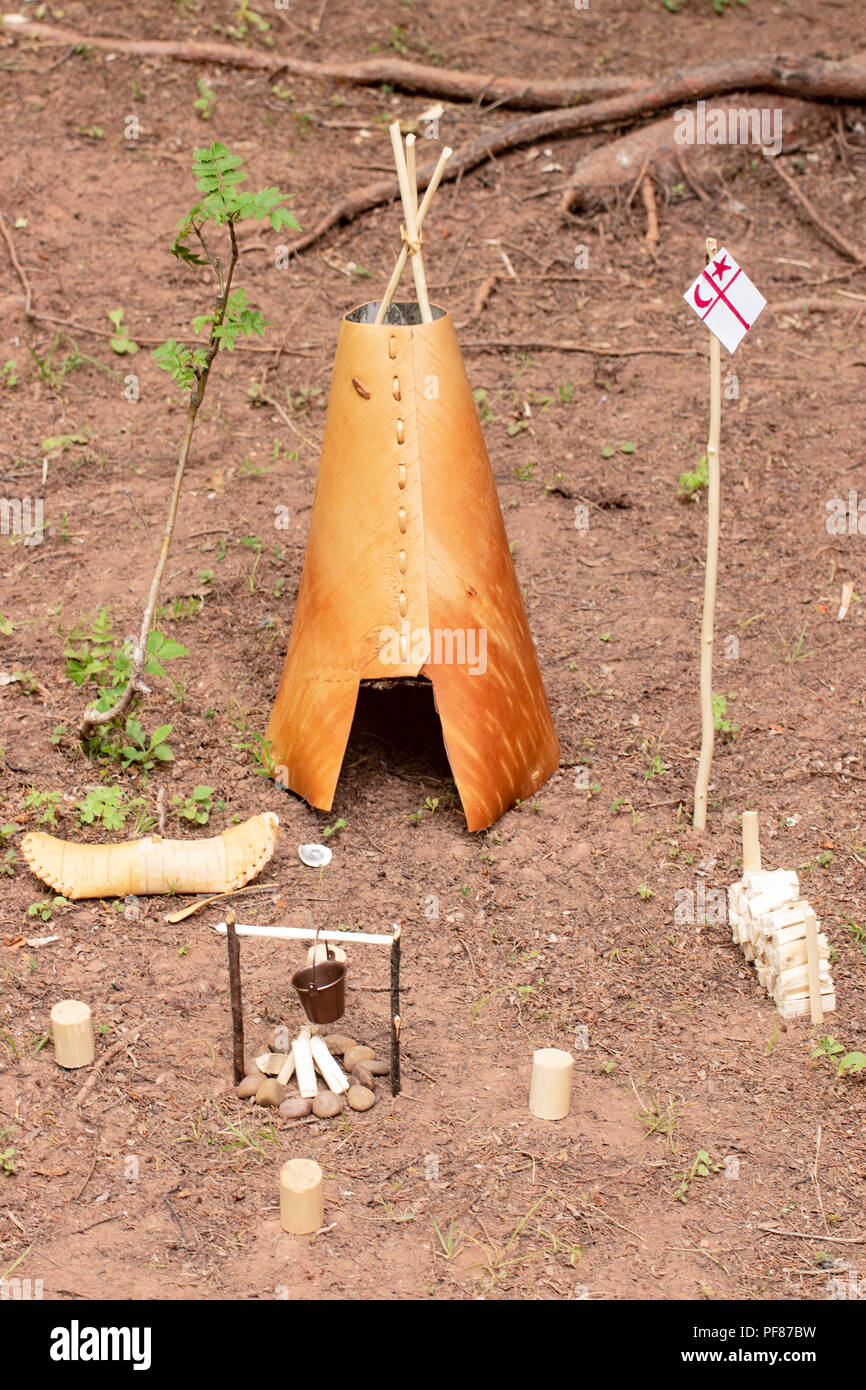 Replica in miniatura di un canadese prima nazione wigwam, canoa, una buca per il fuoco, fumatore e bandiera pole. Foto Stock