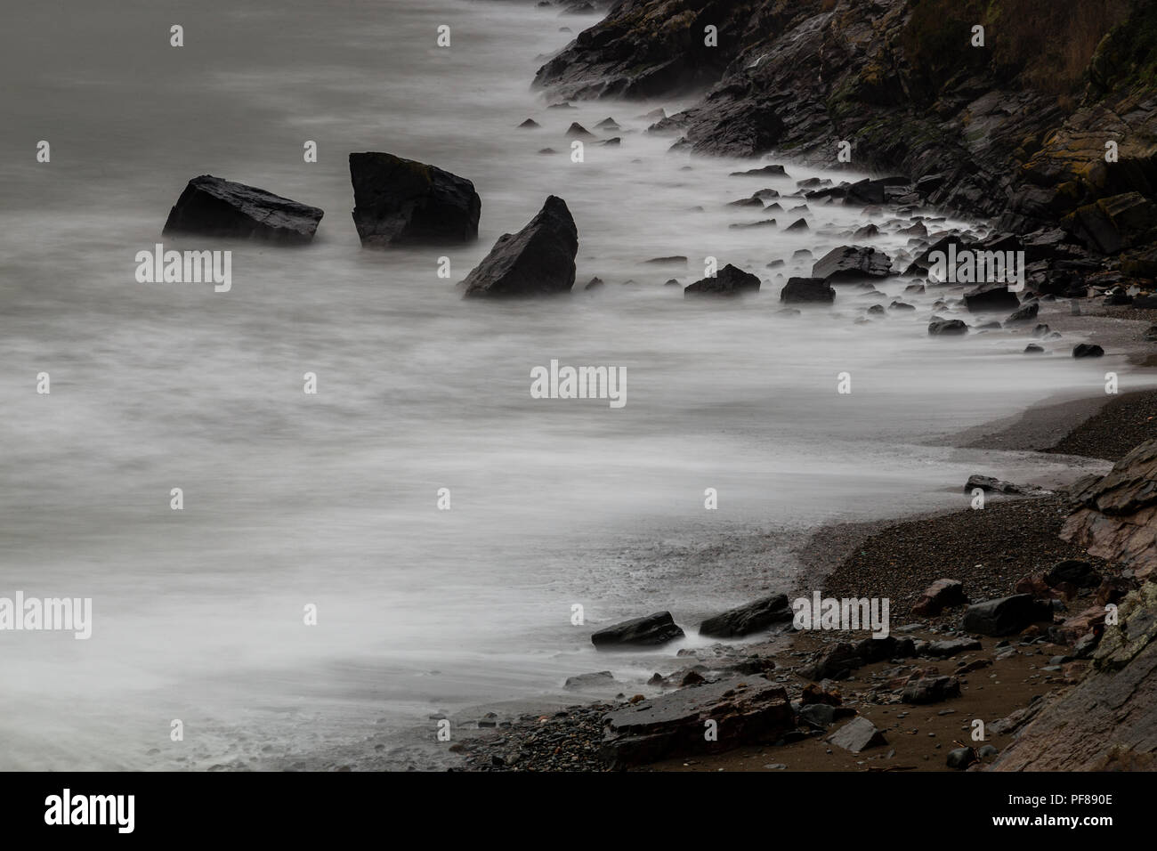 Sfocato onde su una spiaggia rocciosa a Porth Ysgo, il Galles del Nord Foto Stock