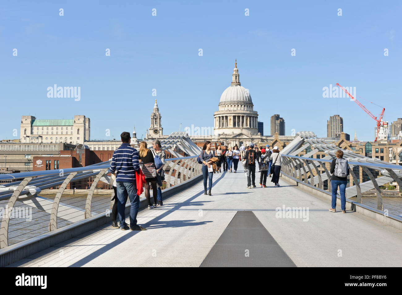 Pedoni che attraversano il Millennium Bridge con la cupola della cattedrale di St Paul in distanza, London, England, Regno Unito Foto Stock