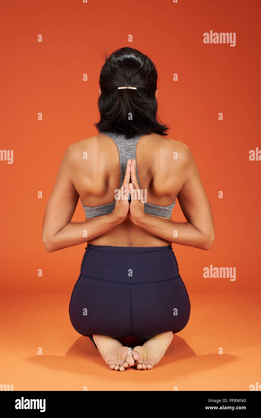 Invertire la preghiera lo yoga pone la donna mostra su arancione di sfondo per studio Foto Stock
