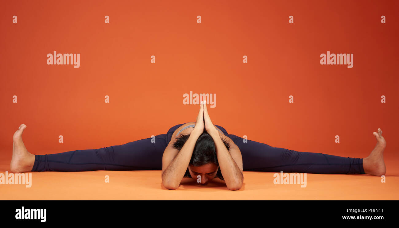 Ampio angolo seduti piegare in avanti lo yoga pone la donna mostra su sfondo per studio Foto Stock