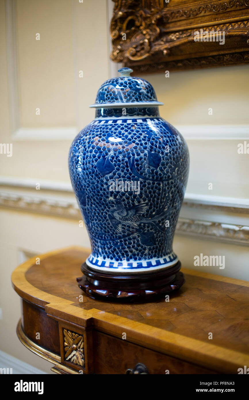 Closeup cinese di blu e bianco urna decorativo su un'antica credenza in legno di noce Foto Stock