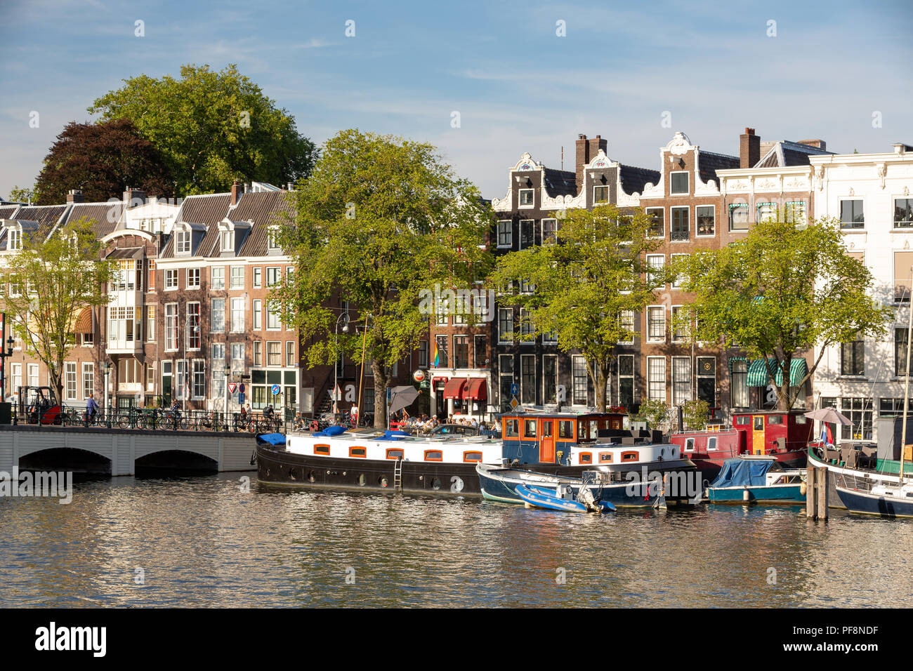 AMSTERDAM, Paesi Bassi - 6 agosto 2018: una grande casa barca sul fiume Amstel con le tradizionali case sul canale. Foto Stock