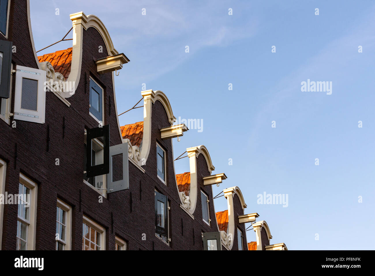 AMSTERDAM, Paesi Bassi - 6 agosto 2018: una fila di Dutch ornati tetti a capanna con ganci mobili. Foto Stock
