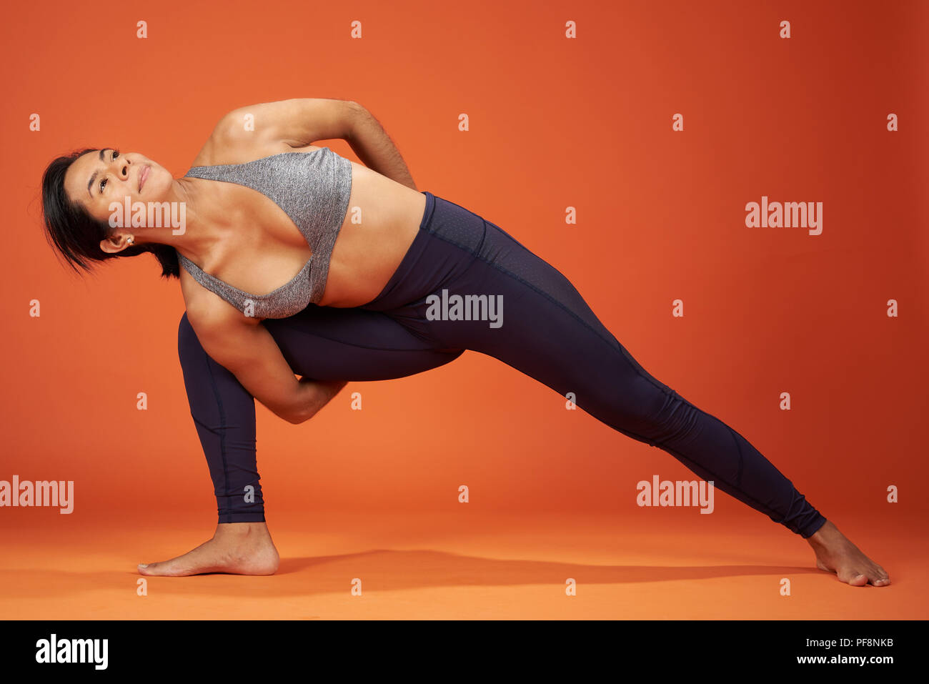 Lo Yoga pone legato laterale ad angolo donna mostra su orange Colore di sfondo Foto Stock