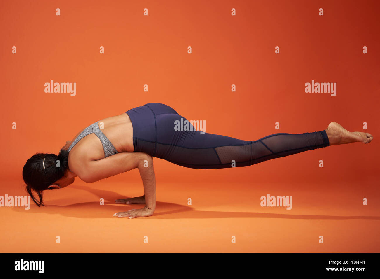 Lo Yoga pone dedicata alla salvia Koundinya mostra ragazza di colore arancione di sfondo per studio Foto Stock