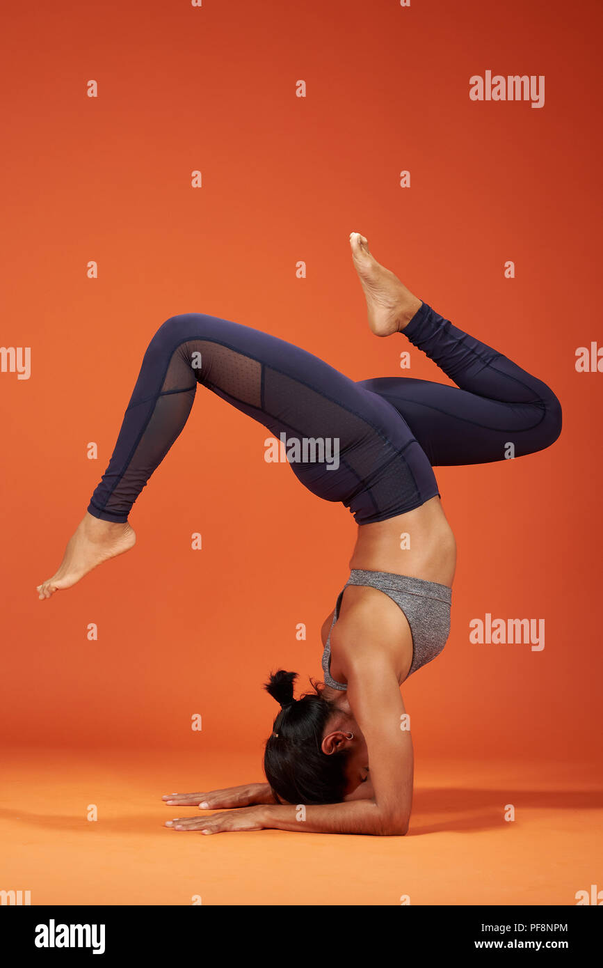 Handstand con split yoga pone la donna mostra su sfondo per studio Foto Stock