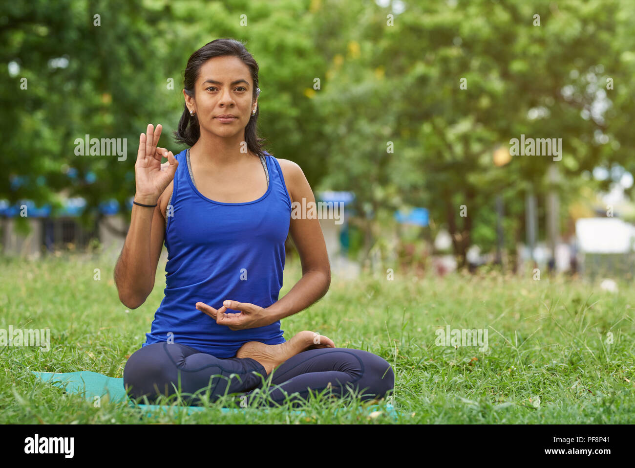 Fare yoga in tema di parcheggio. Giovane donna fare yoga nel parco verde di sfondo Foto Stock