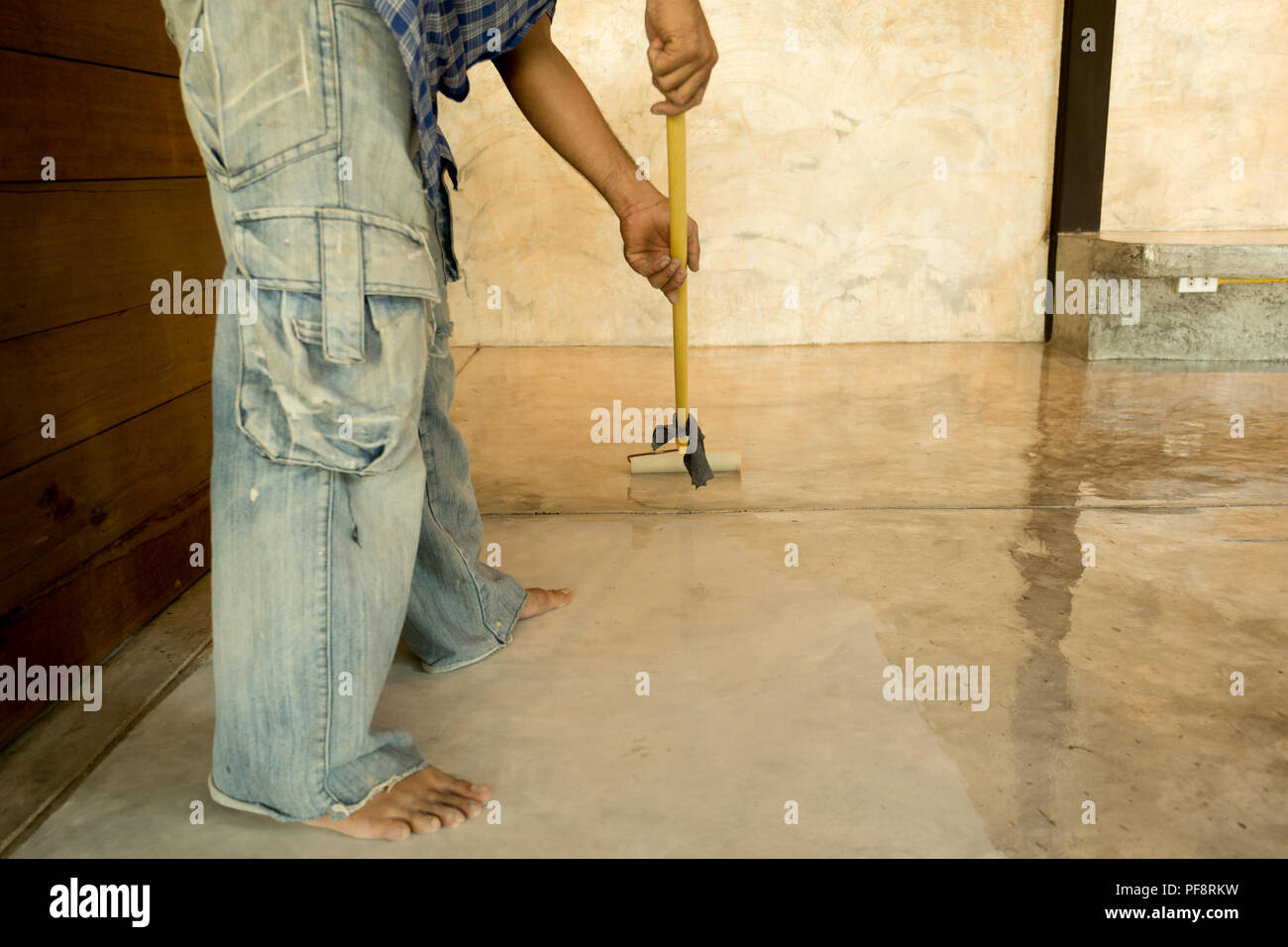 Lavori di laccatura pavimenti in calcestruzzo usando il rullo per rivestire Foto Stock