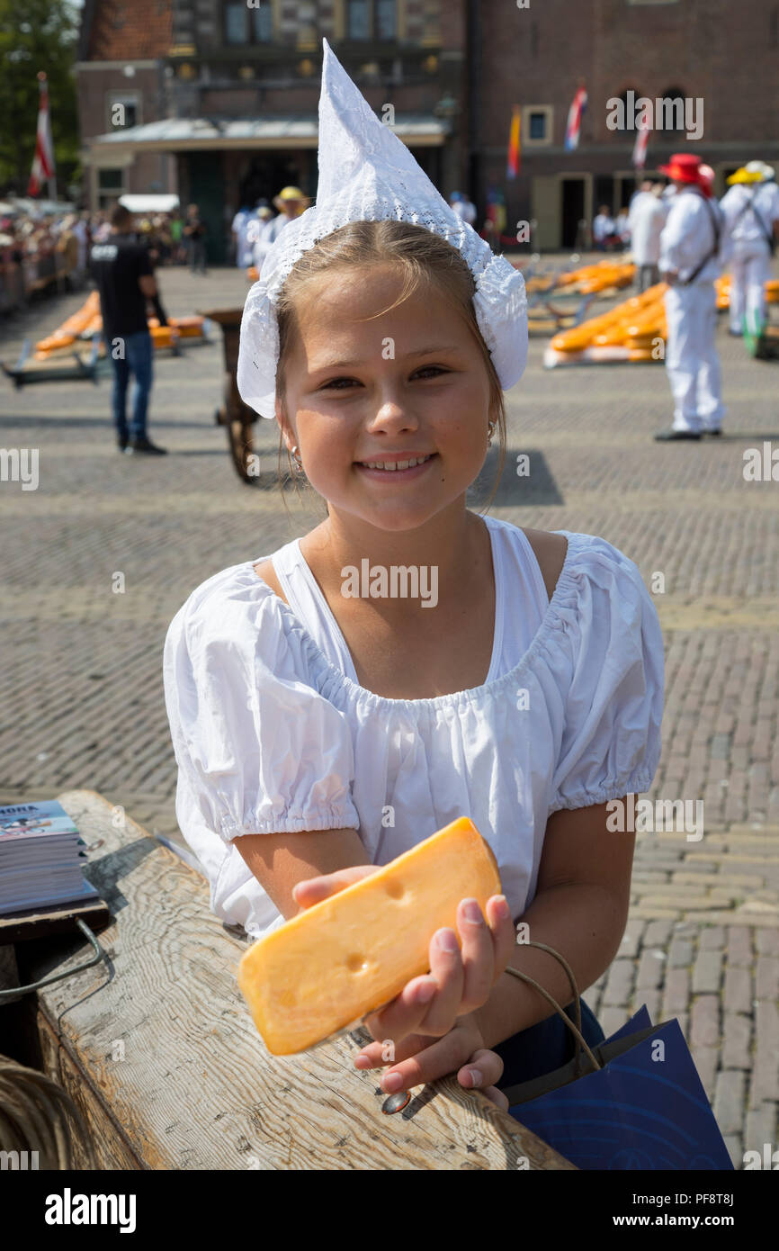 Alkmaar, Paesi Bassi - Luglio 20, 2018: Formaggio girl, kaasmeisje, in costume tradizionale è che mostra un campione di formaggio al mercato del formaggio di Alkmaar Foto Stock