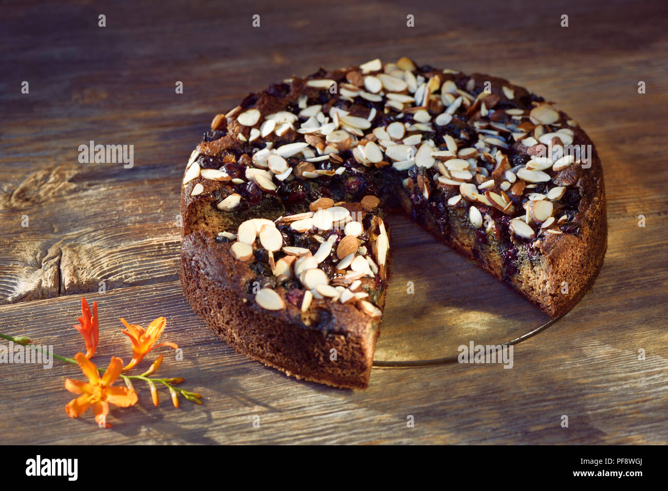 Una sana fatti in casa a base di pane alla banana, senza zucchero con la farina di mandorle, le bacche e le mandorle in una tabella, artistico in stile country food still life su legno rustico Foto Stock