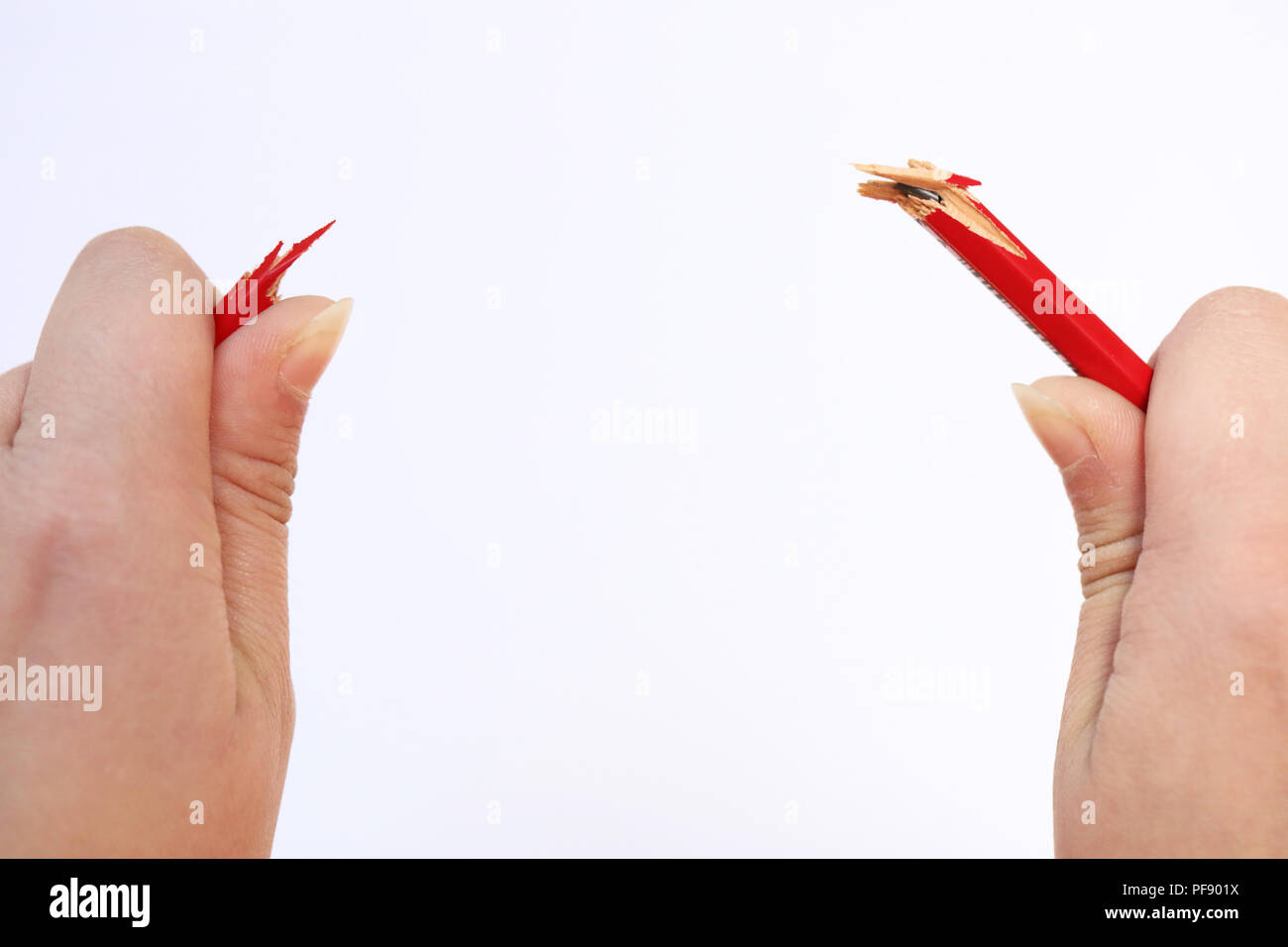 Due mani tenendo una matita rossa che ha appena scattato sotto la pressione. Concetto di stress, gestione di rabbia, pressione sul posto di lavoro, genitorialità un Foto Stock