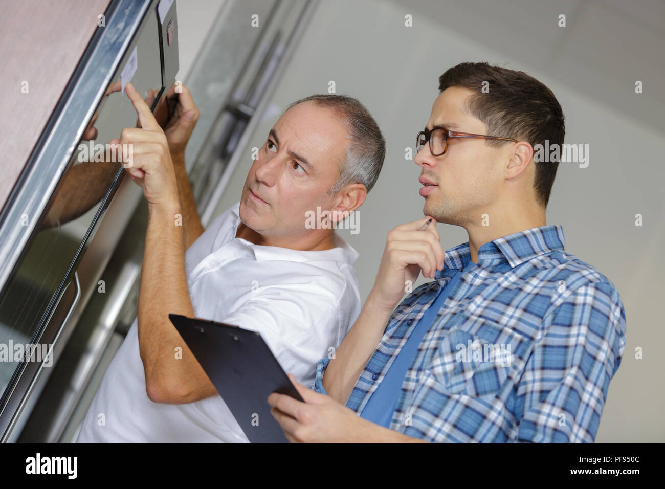 Due lavoratori ispezione di windows in officina Foto Stock