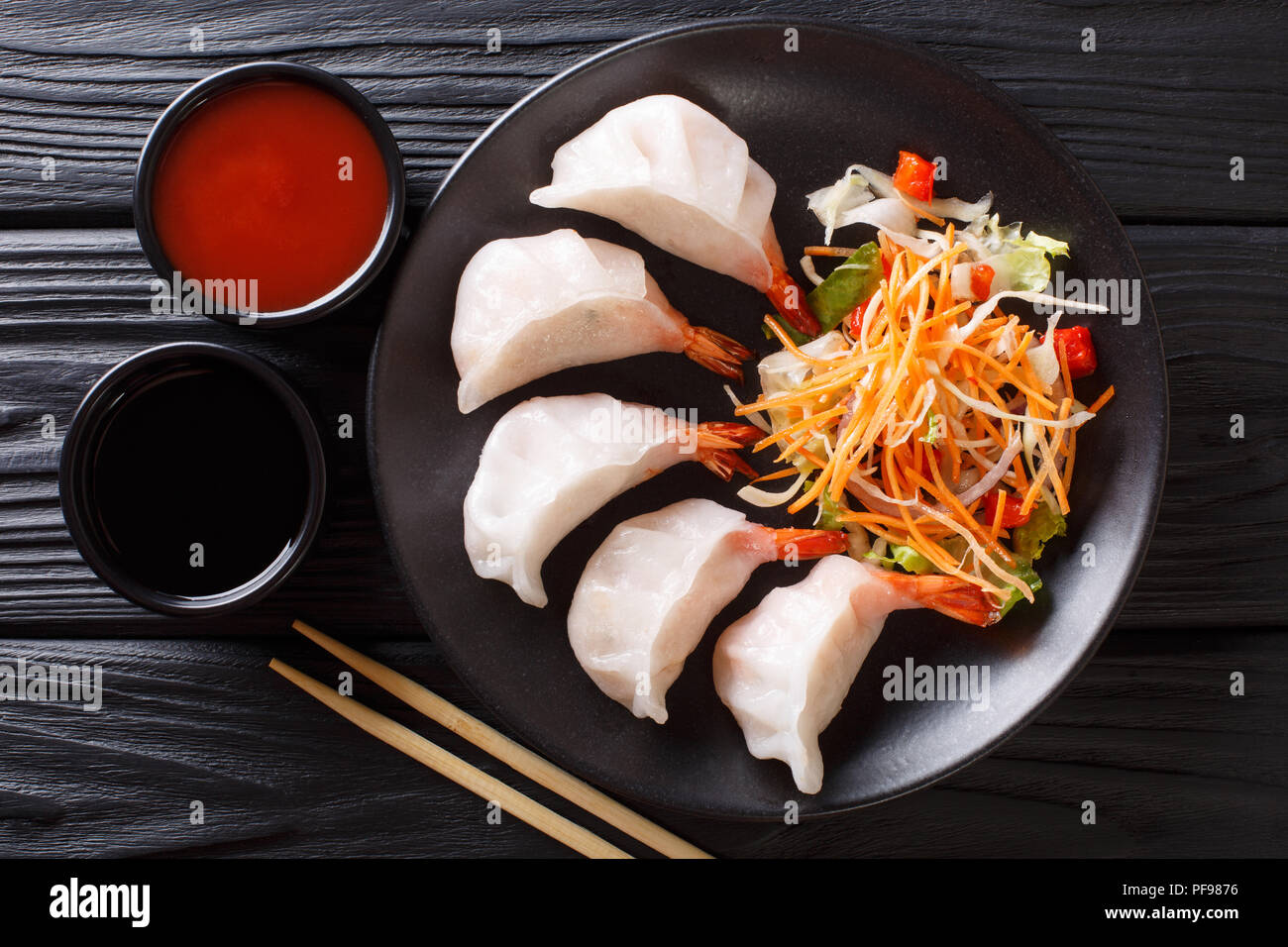 Gnocchi cinesi jiaozi con gamberi sono serviti con insalata di verdure close-up su una piastra. parte superiore orizzontale vista da sopra Foto Stock