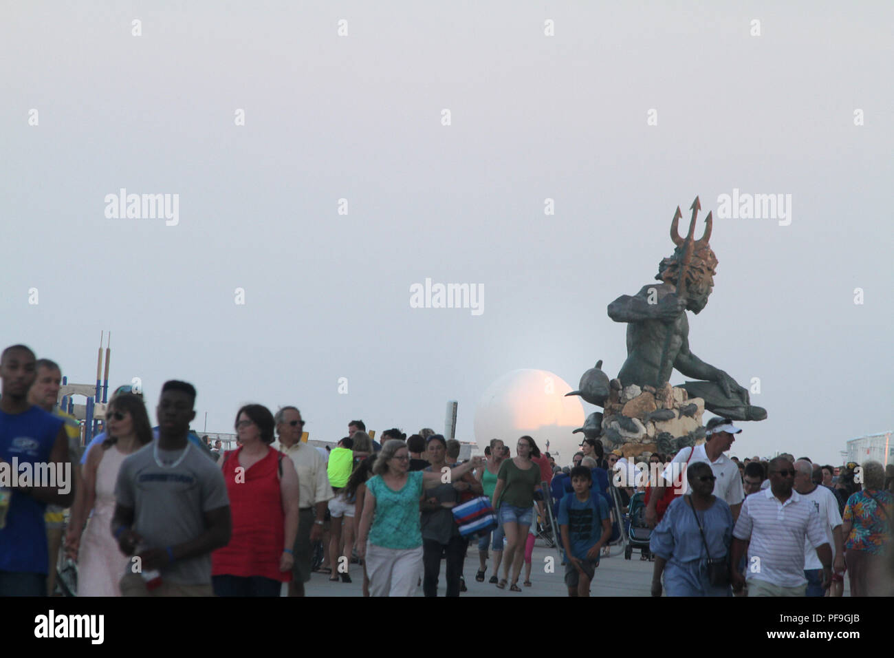 Re Nettuno statua visto in lontananza sul lungomare di Virginia Beach, Stati Uniti d'America. I turisti a piedi sul lungomare. Foto Stock