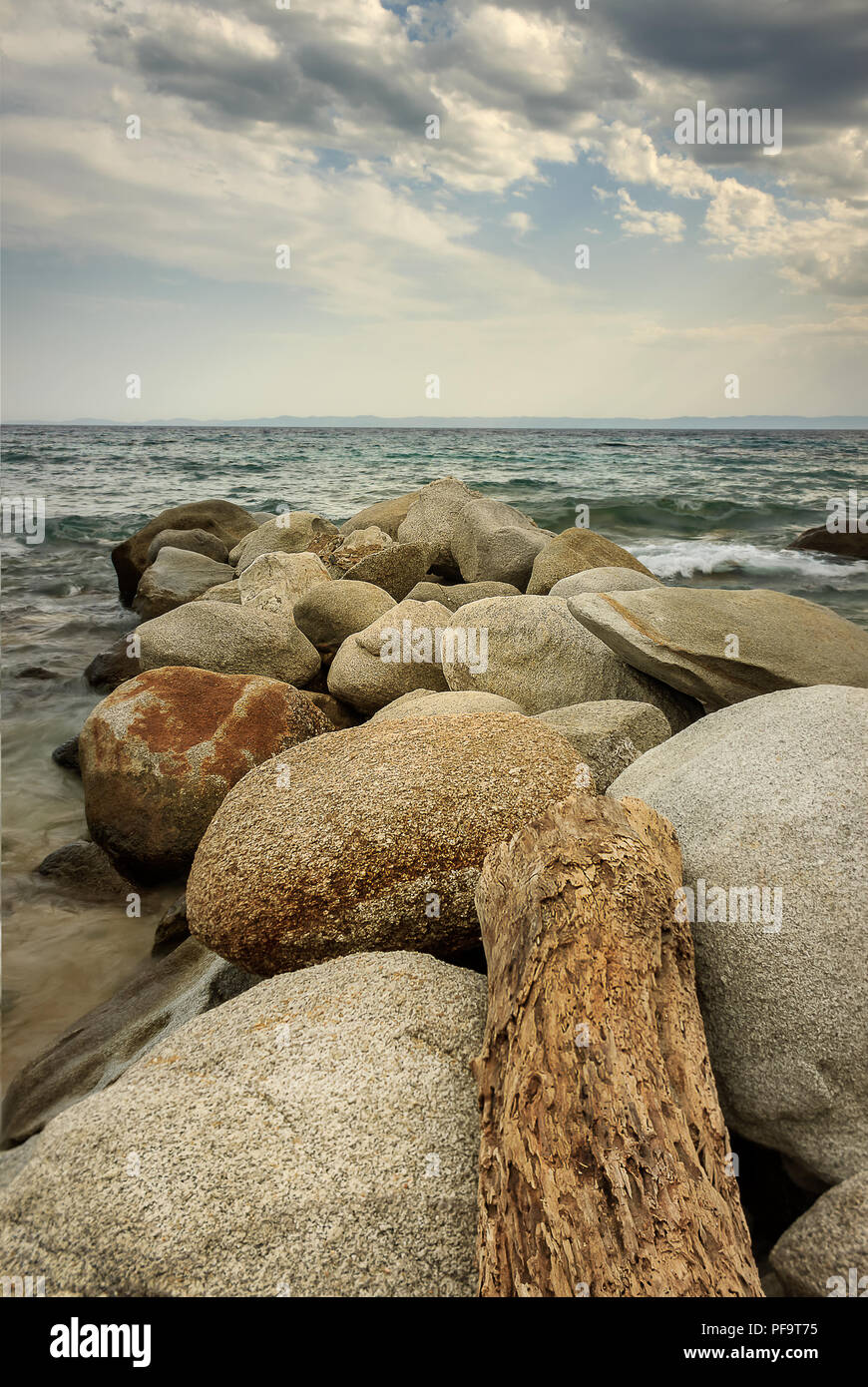 Scenic Kalogria spiaggia spiaggia di roccia, legno e acqua turchese e moody sky Foto Stock